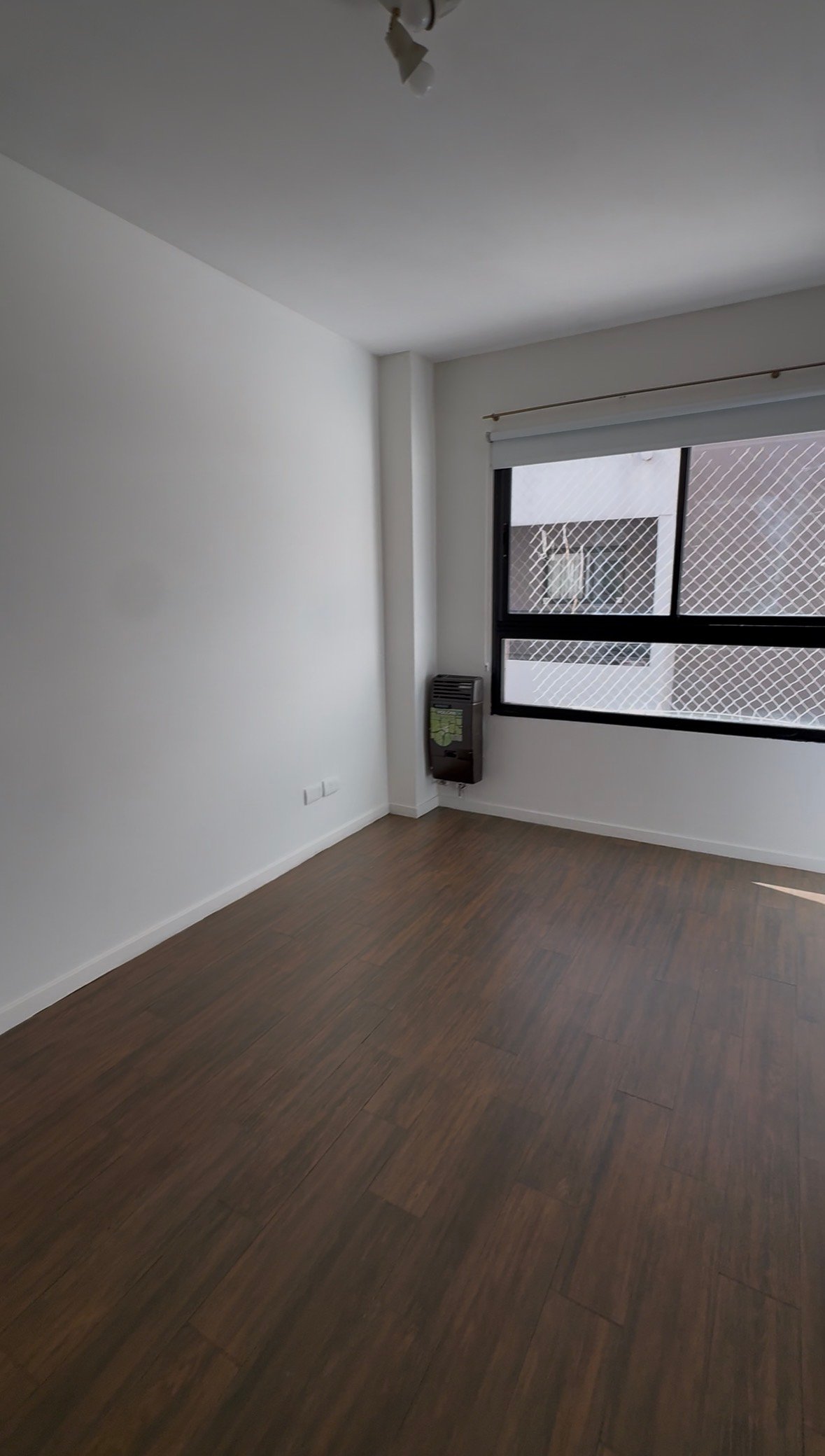 Dormitorio vacío con piso vinílico y calefactor de tiro balanceado