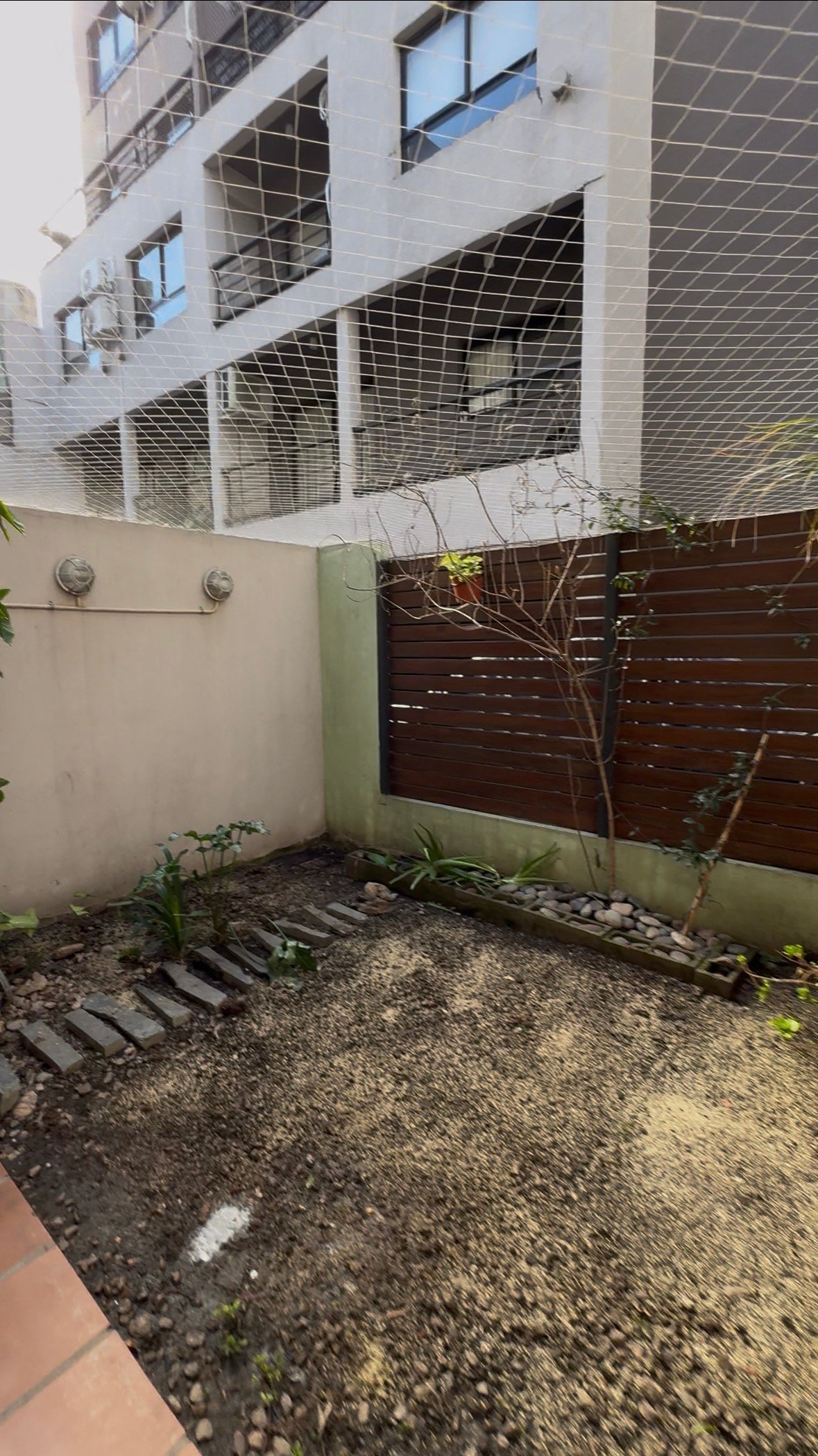 Patio con jardín en su estado actual, con cantero y solado de canto rodado